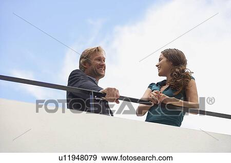 Stock Photo - Young businessman and business woman on balcony.. Fotosearch