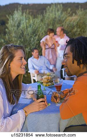Picture - Young men and women at a barbecue. Fotosearch