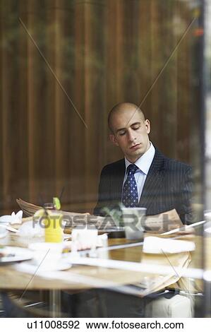 Stock Image - A businessman in a restaurant with a newspaper. Fotosearch