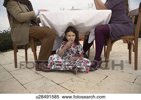 Girl (9-11) eating cake under dinner table View Large Photo Image Stock Photography - Girl (9-11) eating cake under dinner table. Fotosearch