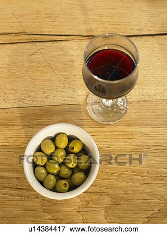 Stock Photo - Glass of red wine and olives on wooden table. Fotosearch