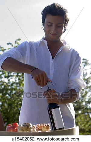 Stock Image - Man opening a bottle of wine. Fotosearch