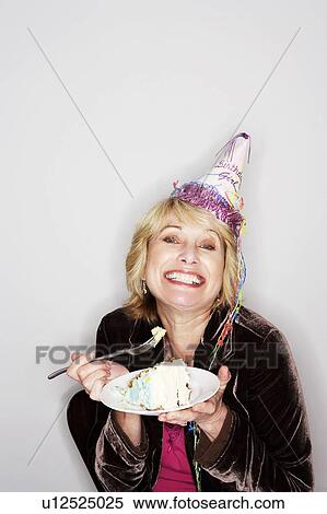 Stock Photography - Senior woman eating birthday cake. Fotosearch