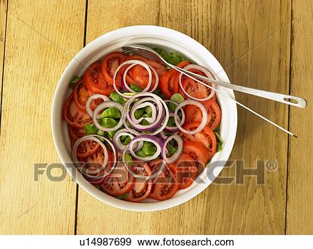 Stock Photo - Tomato and onion salad in a white bowl on wooden table. Fotosearch
