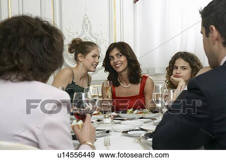 Two women talking at dinner table with family View Large Photo Image Stock Photo - Two women talking at dinner table with family. Fotosearch