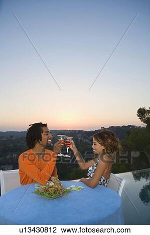 Stock Image - Young couple having dinner at sunset. Fotosearch