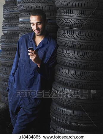 Mechanic standing by stacks of tires View Large Photo Image Stock Photography - Mechanic standing by stacks of tires. Fotosearch