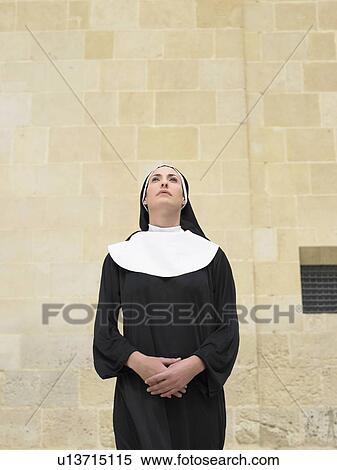 Stock Photography - Portrait of nun clasping hands looking up, Alicante, Spain,. Fotosearch