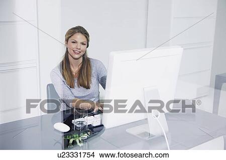 Woman in Office at computer desk smiling. View Large Photo Image Picture - Woman in Office at computer desk smiling.. Fotosearch