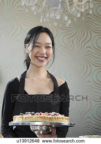 Young waitress holding dessert, smiling, portrait View Large Photo Image Stock Photo - Young waitress holding dessert, smiling, portrait. Fotosearch