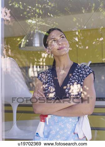 Stock Photo - Young woman daydreaming whilst cleaning. Fotosearch