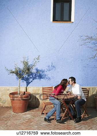 Stock Photo - Couple sitting on garden terrace, kissing. Fotosearch