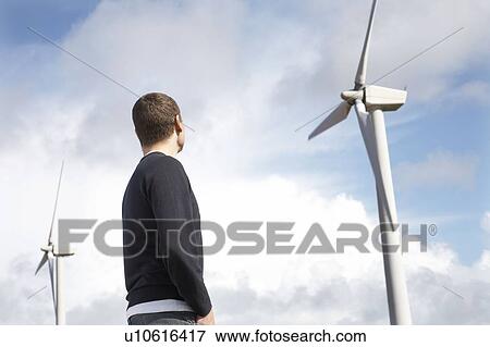 Stock Photo - Man looking at wind turbines. Fotosearch