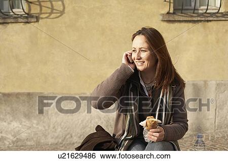 Mature woman on phone eating sandwich View Large Photo Image Stock Photograph - Mature woman on phone eating sandwich. Fotosearch