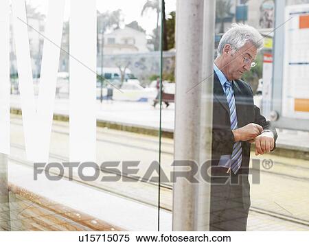 Senior businessman checking watch waiting by tramway View Large Photo Image Stock Photography - Senior businessman checking watch waiting by tramway. Fotosearch