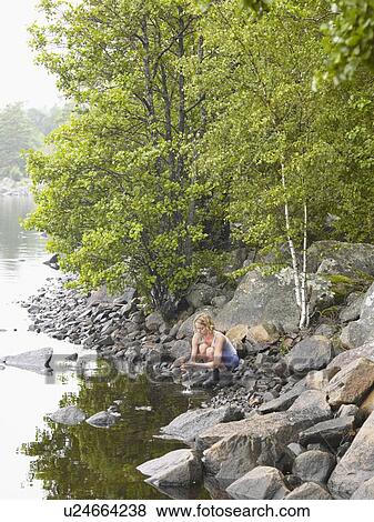 Stock Photo - Woman washing her hands in a lake.. Fotosearch