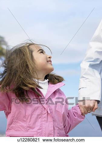 Young girl (6-8) looking up at mother whilst holding her hand, close-up. Alicante, Spain. View Large Photo Image Stock Image - Young girl (6-8) looking up at mother whilst holding her hand, close-up. Alicante, Spain.. Fotosearch