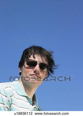 Young man looking at camera wearing sunglasses. View Large Photo Image Stock Image - Young man looking at camera wearing sunglasses.. Fotosearch
