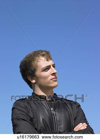 Stock Image - Young man outdoors looking out at something.. Fotosearch