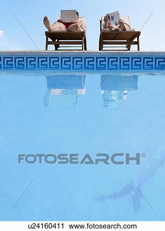 Couple sunbathing by swimming pool, man using laptop View Large Photo Image Stock Image - Couple sunbathing by swimming pool, man using laptop. Fotosearch