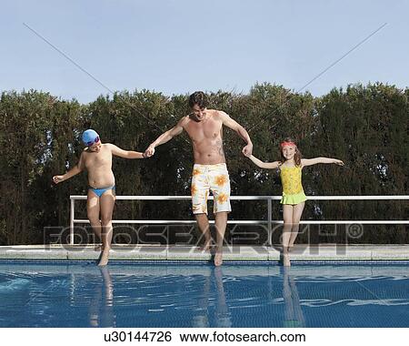 Stock Photograph - Father and children dipping toes in pool. Fotosearch