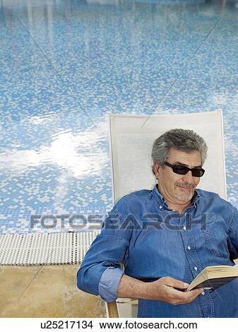 Picture - Senior man wearing sunglasses relaxing in deckchair. Fotosearch