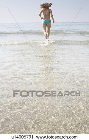 Stock Image - Woman running into sea. Fotosearch