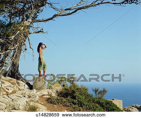 Woman standing on a large rock looking out over the sea. View Large Photo Image Stock Photo - Woman standing on a large rock looking out over the sea.. Fotosearch