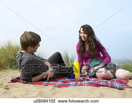 Couple lying on blanket on sand dune View Large Photo Image Stock Image - Couple lying on blanket on sand dune. Fotosearch