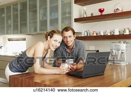 Couple smiling at camera in kitchen View Large Photo Image Stock Image - Couple smiling at camera in kitchen. Fotosearch