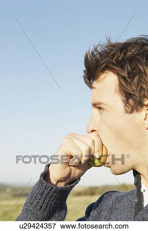 Man eating apple in countryside View Large Photo Image Stock Photo - Man eating apple in countryside. Fotosearch