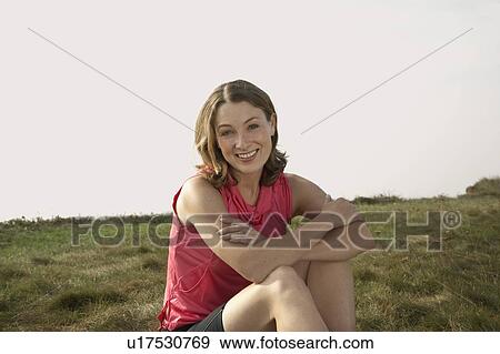 Stock Photo - Portrait of a woman sitting on grass.. Fotosearch