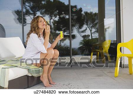 Stock Image - Woman blowing bubbles.. Fotosearch
