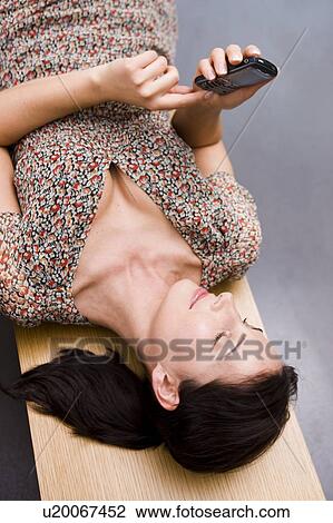 Woman laying on a bench text messaging View Large Photo Image Stock Image - Woman laying on a bench text messaging. Fotosearch