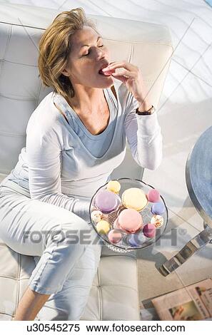 Stock Photography - Woman relaxing, eating cookie. Fotosearch