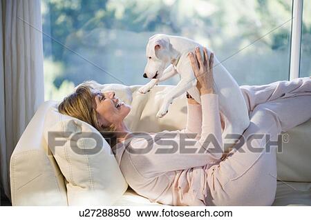 Stock Image - Woman Relaxing, Playing With Dog. Fotosearch