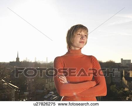 Stock Photography - Woman standing on roof terrace. Fotosearch