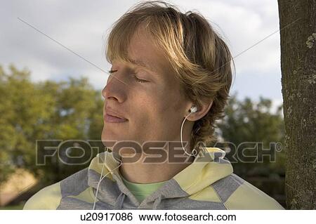 Stock Photograph - Young man with small headphones.. Fotosearch