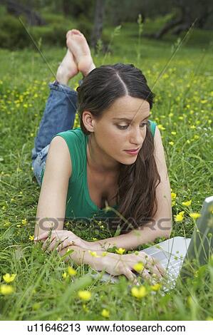 Young woman lying in meadow with laptop. View Large Photo Image Stock Image - Young woman lying in meadow with laptop.. Fotosearch