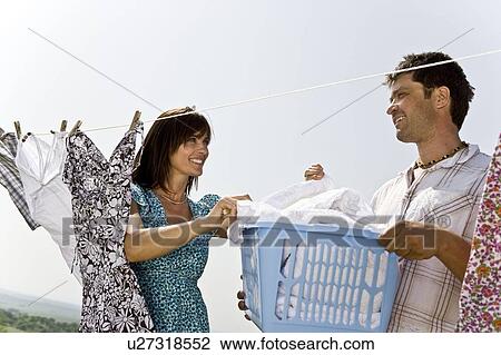 Stock Image - Man helping woman hang clothes. Fotosearch