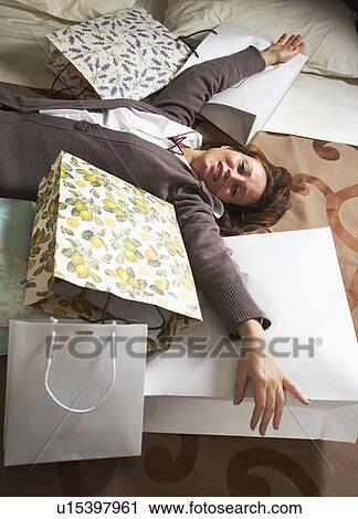 Stock Image - Mature woman on bed with shopping. Fotosearch