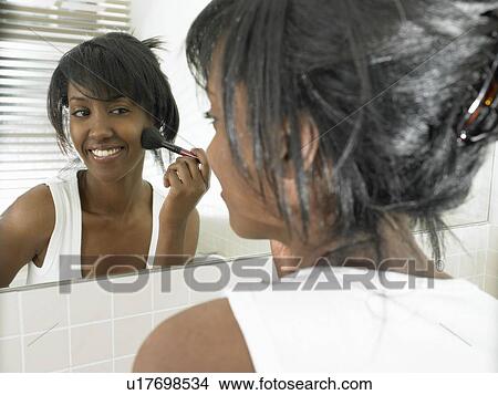 Picture - Woman in bathroom, applying makeup. Fotosearch