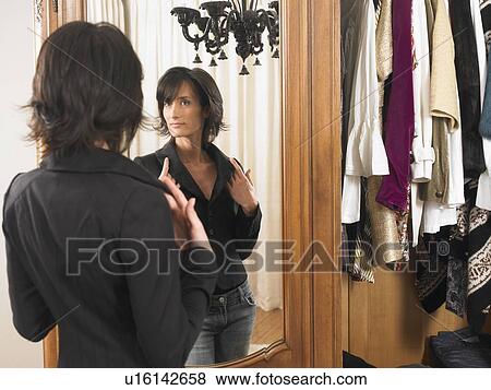 Stock Photo - Woman looking at herself in the mirror. Fotosearch