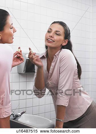Woman reflected in office washroom mirror applying make-up View Large Photo Image Stock Photography - Woman reflected in office washroom mirror applying make-up. Fotosearch