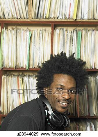 Stock Photo - Disc jockey in front of shelves of records. Fotosearch