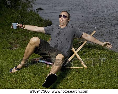 Stock Image - Man breaks garden chair and falls. Fotosearch