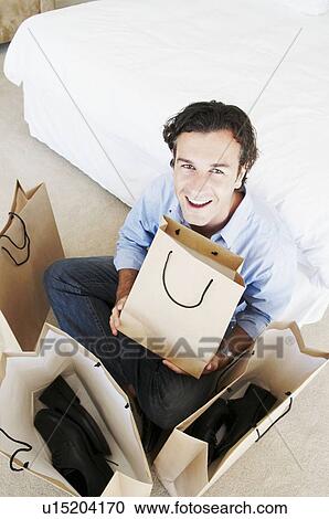 Stock Image - Man smiles holding shopping bags. Fotosearch