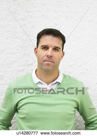 Stock Photo - Man standing by wall, portrait. Fotosearch