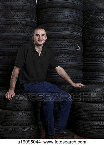 Mechanic sitting on a stack of tires View Large Photo Image Picture - Mechanic sitting on a stack of tires. Fotosearch