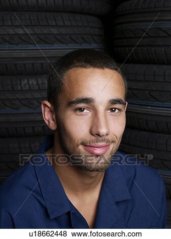 Stock Photo - Mechanic sitting on a stack of tires. Fotosearch
